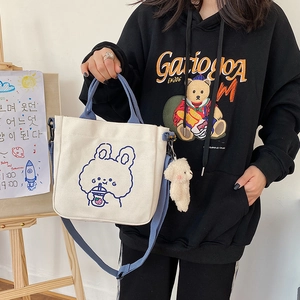 Beige canvas tote bag with blue handles and cartoon bunny print, styled for daily wear