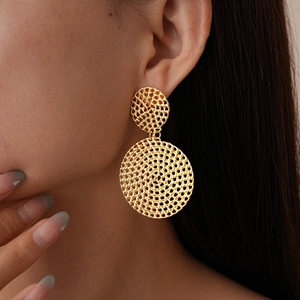Gros plan de boucles d'oreilles géométriques dorées portées par un mannequin de profil