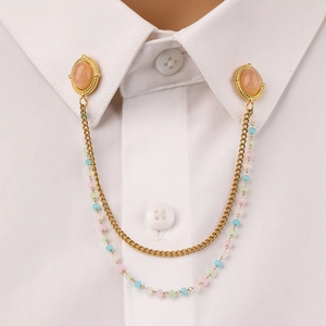 Detail of gold collar pin with pink stones and colorful beads on a white shirt