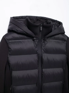 Detailed close-up of hooded black jacket showing stitching, zipper and patchwork textures