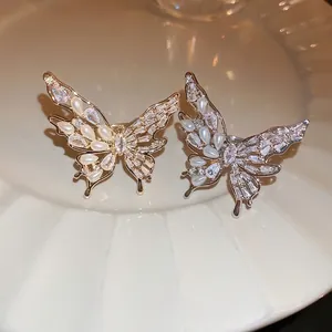 Elegant gold butterfly open ring with zircon and pearls on white porcelain plate