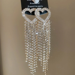 Macro shot of luxurious silver heart earrings with sparkling rhinestone tassels