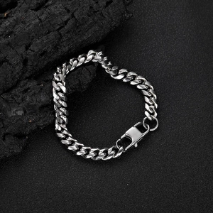 Polished silver stainless steel Cuban link bracelet for men on a dark textured rock