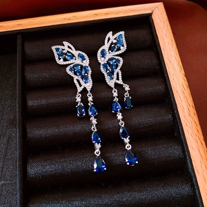 Vue détaillée de boucles d'oreilles papillon bleues avec zircone sur velours noir
