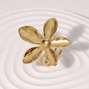 Bague fleurie dorée minimaliste avec texture martelée sur présentoir blanc à ondulations