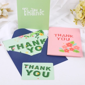 Artistic arrangement of green and pink thank you cards with envelopes on white fabric