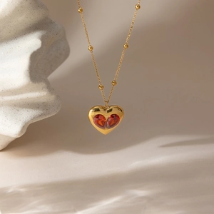 Collier à billes dorées avec pendentif cœur en zircon rouge sur socle en pierre