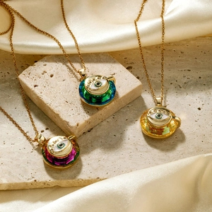 Trois pendentifs tasses mauvais œil en or avec zircons colorés sur pierre et soie