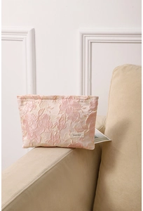 Close-up of pink embossed floral jacquard fabric and H&R BAG label on travel makeup bag