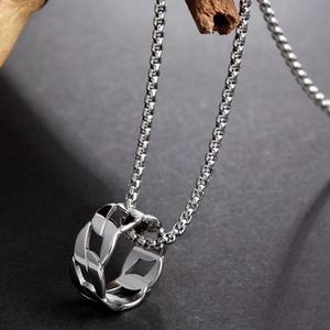 Macro shot of silver titanium steel chain pendant on a textured wooden stand