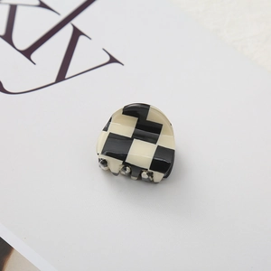 Detail shot of mini black and white checkered hair claw clip with glossy resin finish