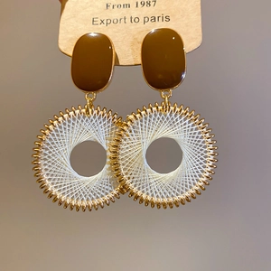 Macro detail of bohemian resin stud and ivory hand-woven round drop earring