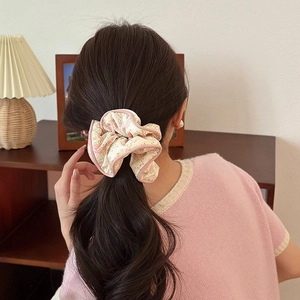 Chouchou en dentelle à fleurs roses porté en chignon pour un style coréen