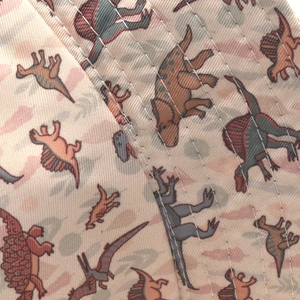 Detailed view of cartoon dinosaur print and reinforced stitching on a reversible sun hat