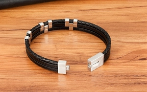 Close-up of men's multilayer braided leather bracelet showing magnetic clasp on wood