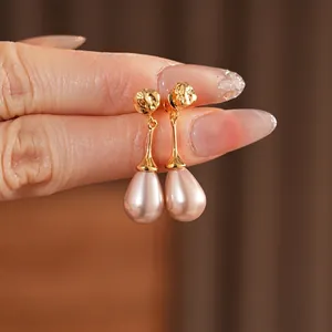 Elegant gold drop earrings with pink teardrop pearls and textured metal sphere details
