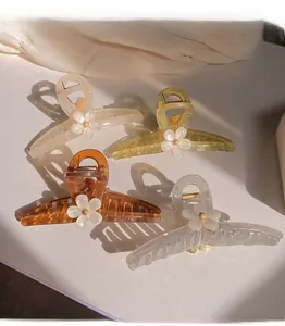 Detailed view of four colorful floral resin hair claws in cream, yellow, and amber tones