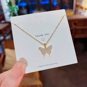 Gros plan du collier papillon doré avec pendentif en zircon sur carte à bijoux