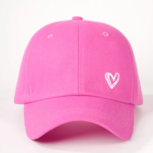 Detail shot of pink cotton baseball cap featuring a white heart print on a six-panel crown
