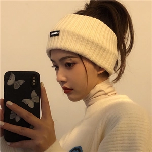 Close-up of a wide cream-colored ribbed knit headband for women in a clean indoor setting