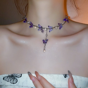 Detail of purple crystal butterfly choker necklace featuring silver chain on woman's collarbone