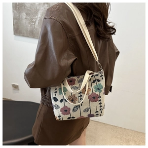 Detailed close-up of a beige canvas handbag with colorful floral patterns and woven straps