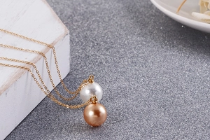 Vue détaillée du collier double épaisseur en titane doré avec perles de nacre blanches