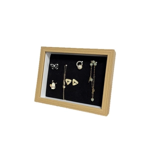 Wooden jewelry display case with black velvet lining showing earrings and necklaces