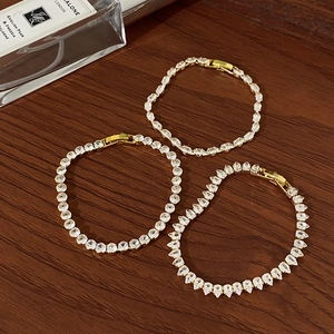 Detailed macro view of three gold-plated tennis bracelets with marquise and pear cut zircons