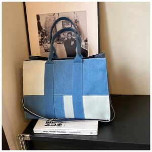Detail of color-blocked denim tote bag showing varied blue textures and sturdy handles