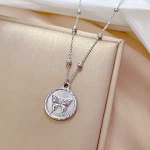 Macro shot of silver titanium steel necklace featuring a round butterfly pendant and bead chain