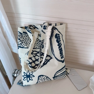 Détail du sac cabas en toile avec imprimé de fruits tropicaux et étiquette de marque tissée