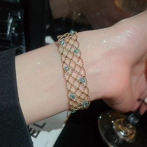 Detailed macro view of a gold mesh lace bracelet featuring elegant blue crystal beads
