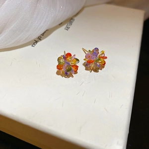 Close-up of colorful crystal flower earrings on a white jewelry box with silk