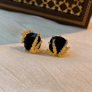 Boucles d'oreilles carrées plaquées or avec cristal noir sur satin blanc