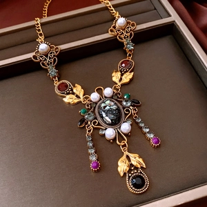 Primo piano di una collana vintage dorata con perle e cristalli colorati in una scatola regalo