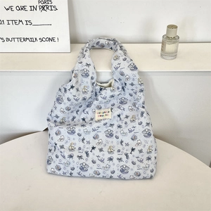 Dettaglio della borsa tote azzurra in seersucker con motivi di gatti e orsi sul tavolo