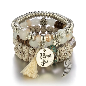Close-up of bohemian layered beaded bracelets with wing charms and tassel detail