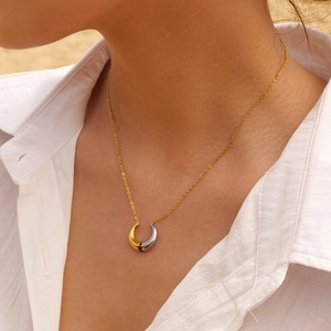 Close-up of dual-tone crescent moon pendant necklace with black stone on model