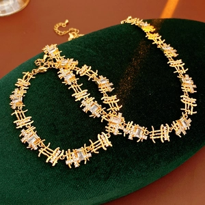 Détail d'ensemble collier et bracelet dorés géométriques sertis de zircons carrés