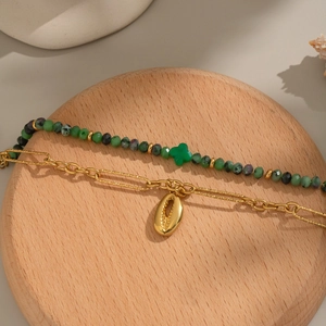 Detail of double-layer natural stone beaded bracelet with golden shell charm on wood