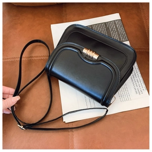 Détail du sac de selle vintage noir avec boucle métallique dorée et texture en similicuir