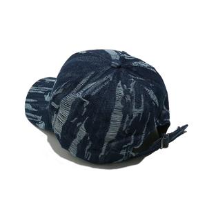 Detail view of distressed navy denim baseball cap with vintage frayed texture and metal buckle