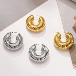 Close-up of chunky ribbed hoop earrings in polished gold and silver steel finish