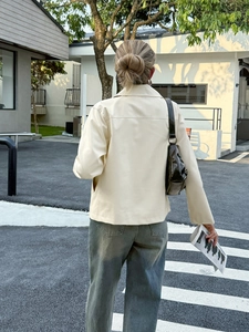 Vista lifestyle all'aperto di una giacca minimalista beige in ecopelle a maniche lunghe