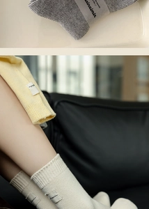 Detail of ribbed knit cotton socks with stitched fabric labels in cream and grey colors