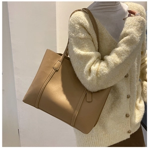 Close-up of a large khaki PU leather tote bag worn by a model for a casual commute look