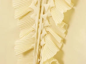 Detailed macro view of the intricate pleated ruffles and chiffon fabric in pale yellow