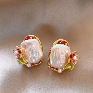Detailed macro view of baroque pearl earrings with golden metal petals and red rhinestones