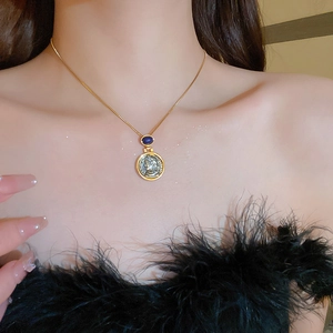 Detail of vintage gold coin necklace with blue gemstone on female model